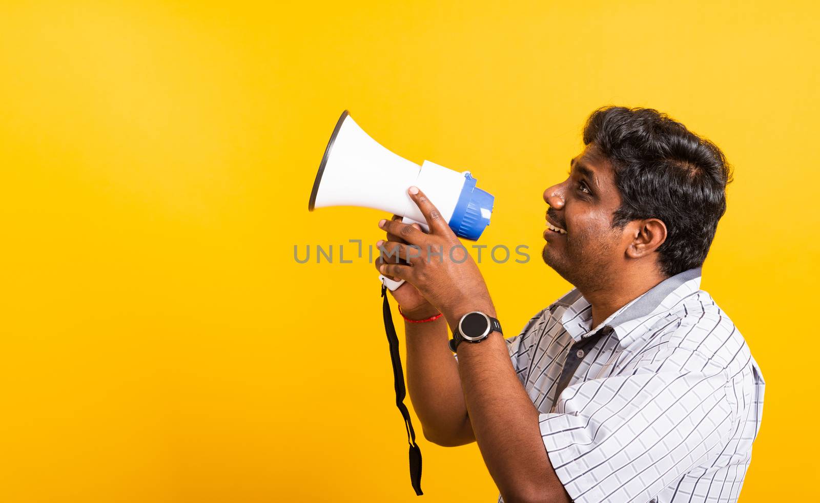 Asian happy portrait young black woman standing to make announcement message shouting screaming in megaphone, studio shot isolated on yellow background with copy space