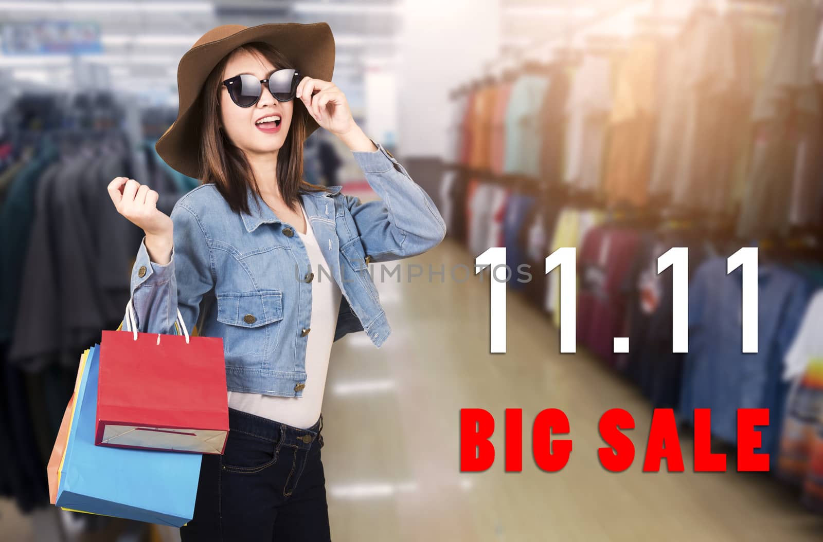 Happy portrait beautiful young woman smiling with sunglasses and hat she excited holding shopping bags multi color on the mall with 11.11 big sale text on space, 11:11 shopping sale concept