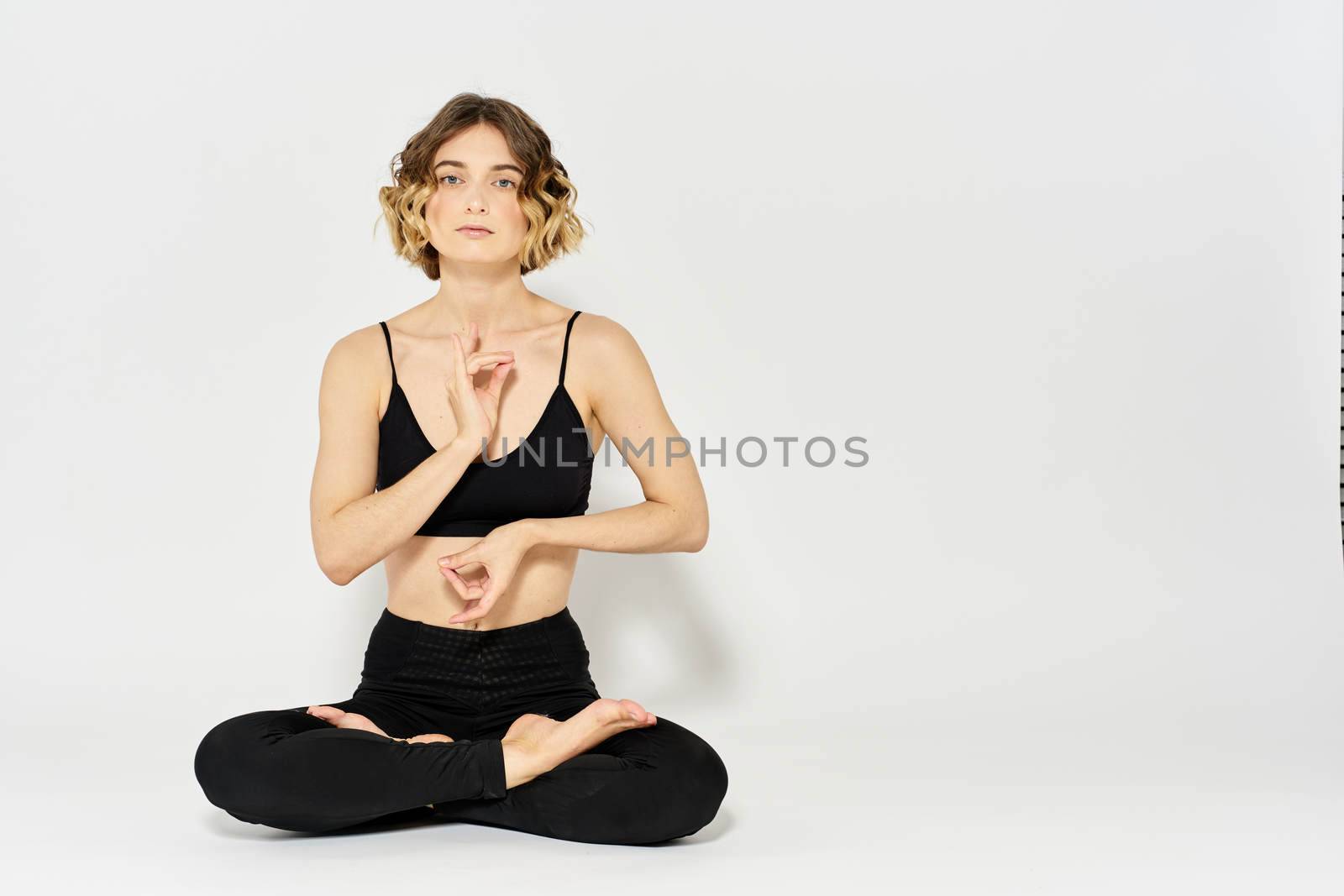 woman in dark clothes sitting on the floor and meditation exercises for legs leggings. High quality photo