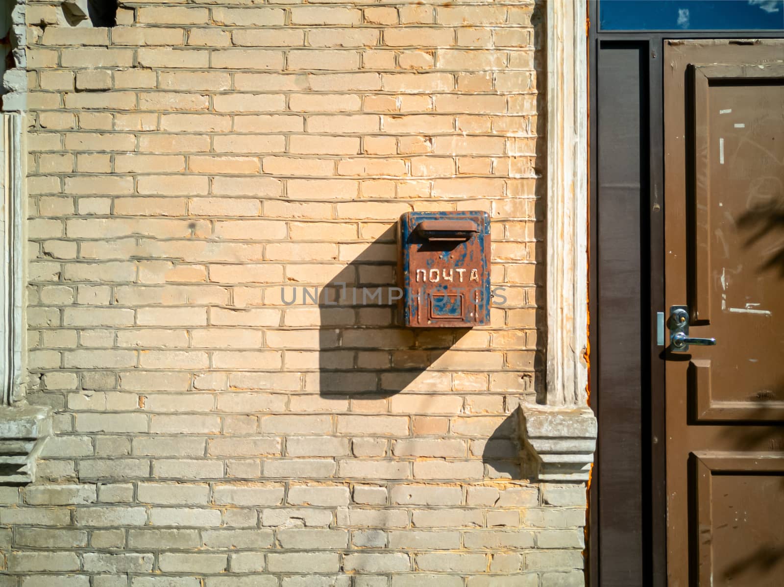 Old letterbox of Soviet era on the wall. Old post box. metal box for mail hanging on dirty wall.