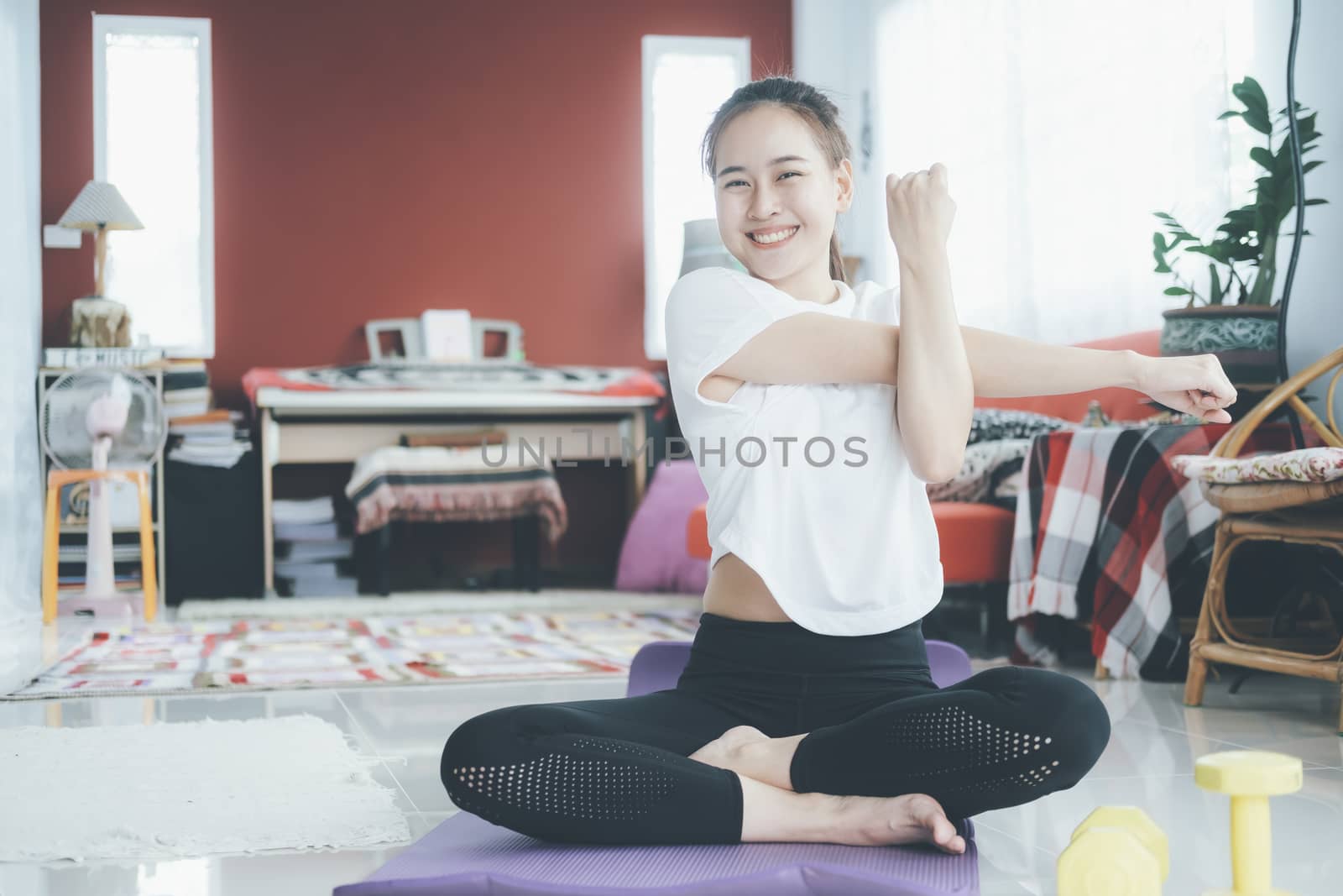 Athletic woman doing fitness stretching exercises at home in the living room. Stay at home and healthy lifestyle.