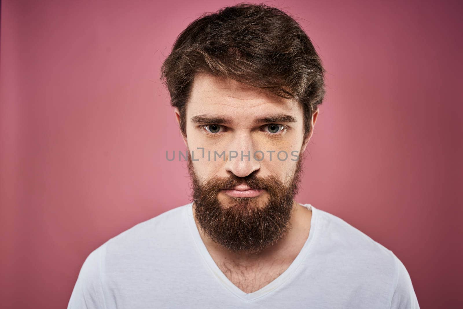 Emotional bearded man in white T-shirt discontent pink background by SHOTPRIME