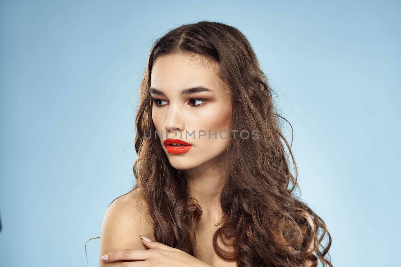 Brunette naked shoulders red lips fashionable hairstyle blue background. High quality photo