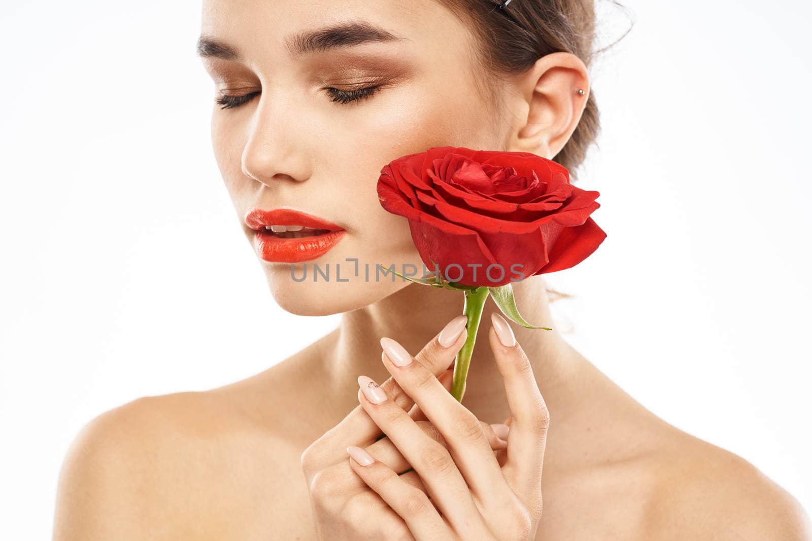 charming brunette girl with makeup on her face and a red rose in her hand. High quality photo