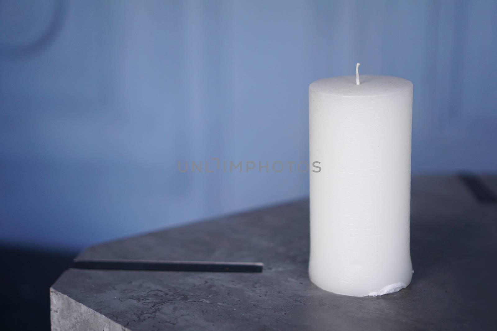 Big white candle on blue background with copy space