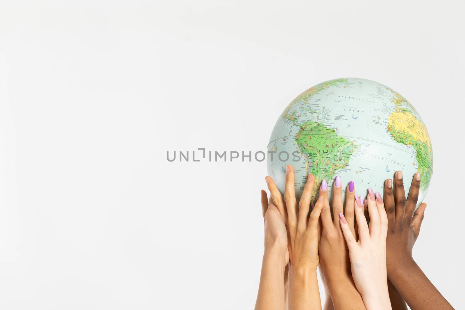 A large globe with all continents is supported by female hands of various races, symbolizing unity, acceptance and racial tolerance.