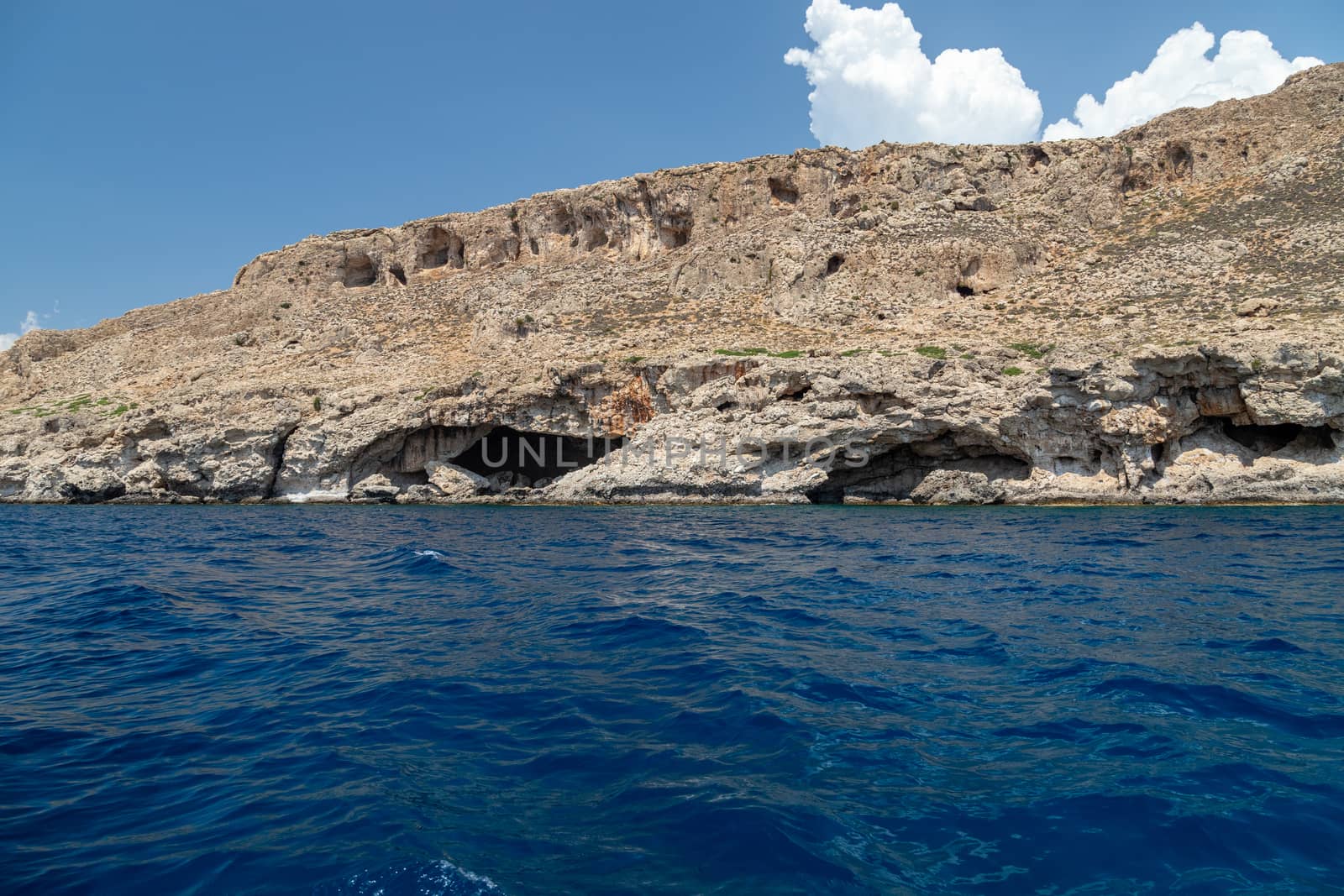 View from a motor boat on the mediterranean sea at the rocky coastline near Stegna on the eastside of Greek island Rhodes on a sunny day in spring