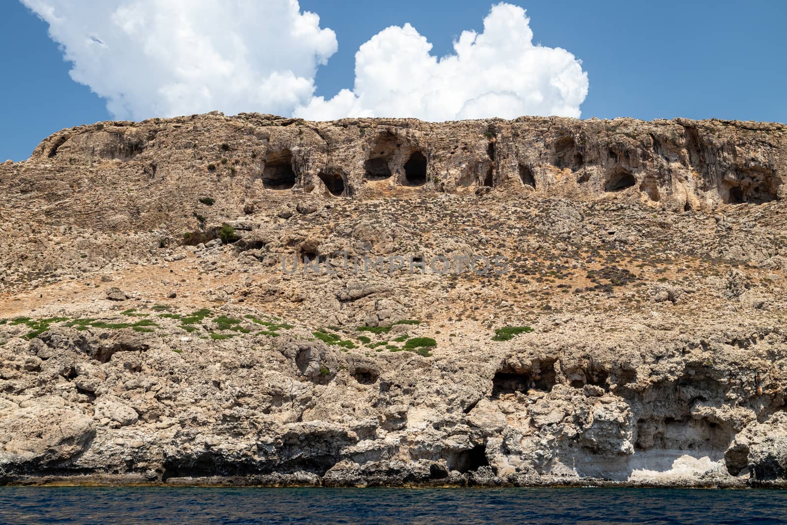 View from a motor boat on the mediterranean sea at the rocky coastline near Stegna on the eastside of Greek island Rhodes on a sunny day in spring