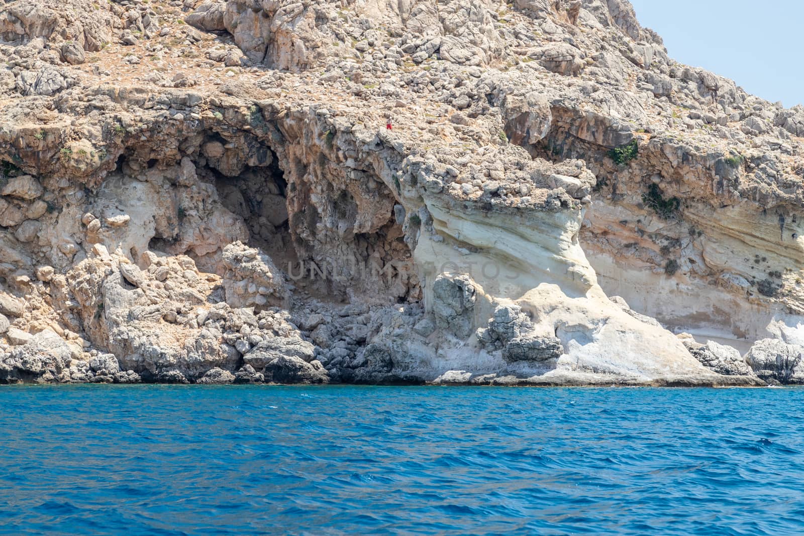 View from a motor boat on the mediterranean sea at the rocky coastline near Stegna on the eastside of Greek island Rhodes on a sunny day in spring