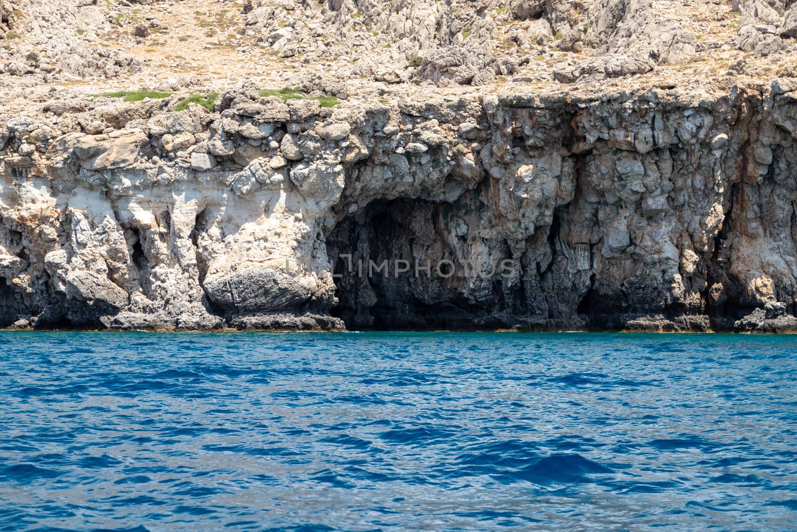 View from a motor boat on the mediterranean sea at the rocky coastline near Stegna on the eastside of Greek island Rhodes on a sunny day in spring