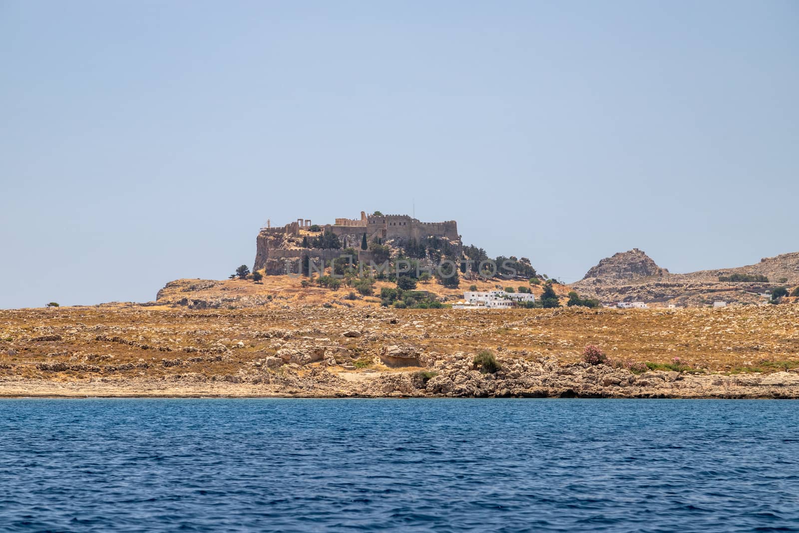 View from a motor boat on the mediterranean sea at the rocky coastline near Lindos on the eastside of Greek island Rhodes on a sunny day in spring