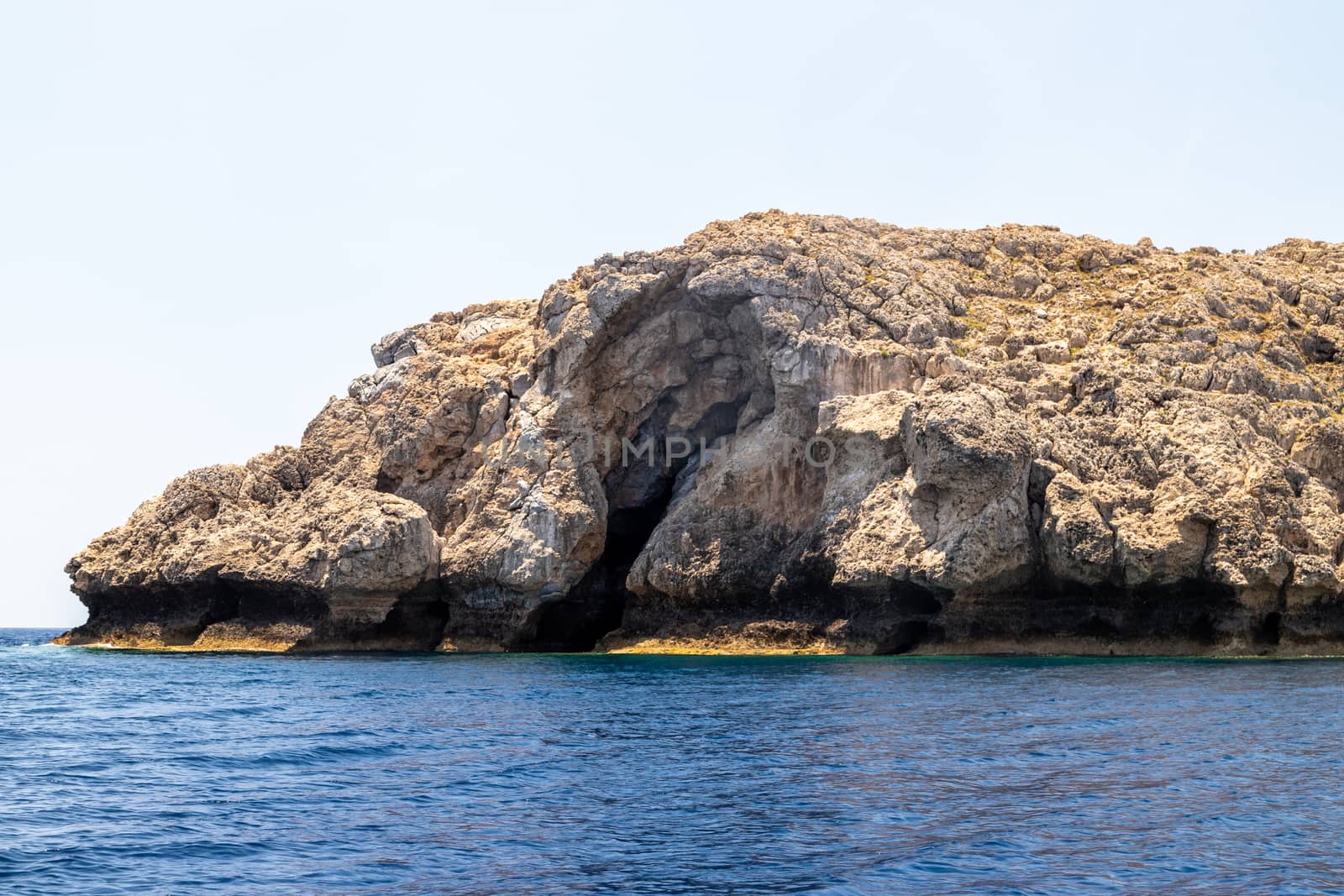 View from a motor boat on the mediterranean sea at the rocky coastline near Lindos on the eastside of Greek island Rhodes on a sunny day in spring