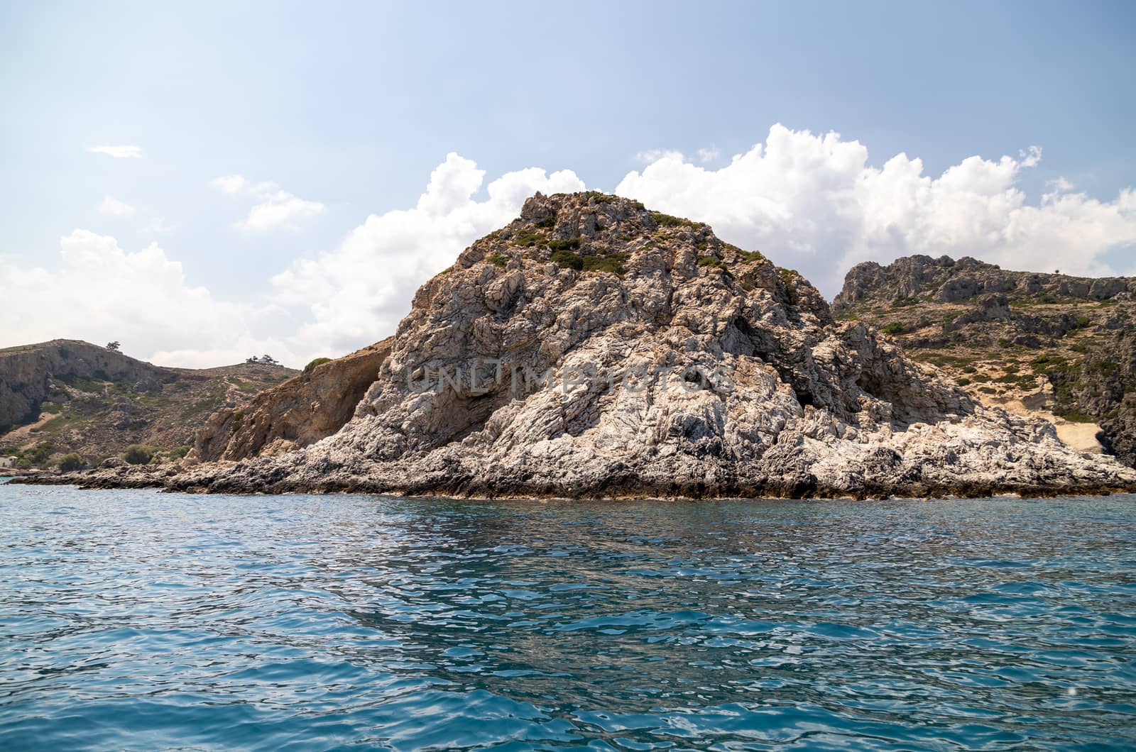 View from a motor boat on the mediterranean sea at the rocky coastline near Stegna on the eastside of Greek island Rhodes on a sunny day in spring