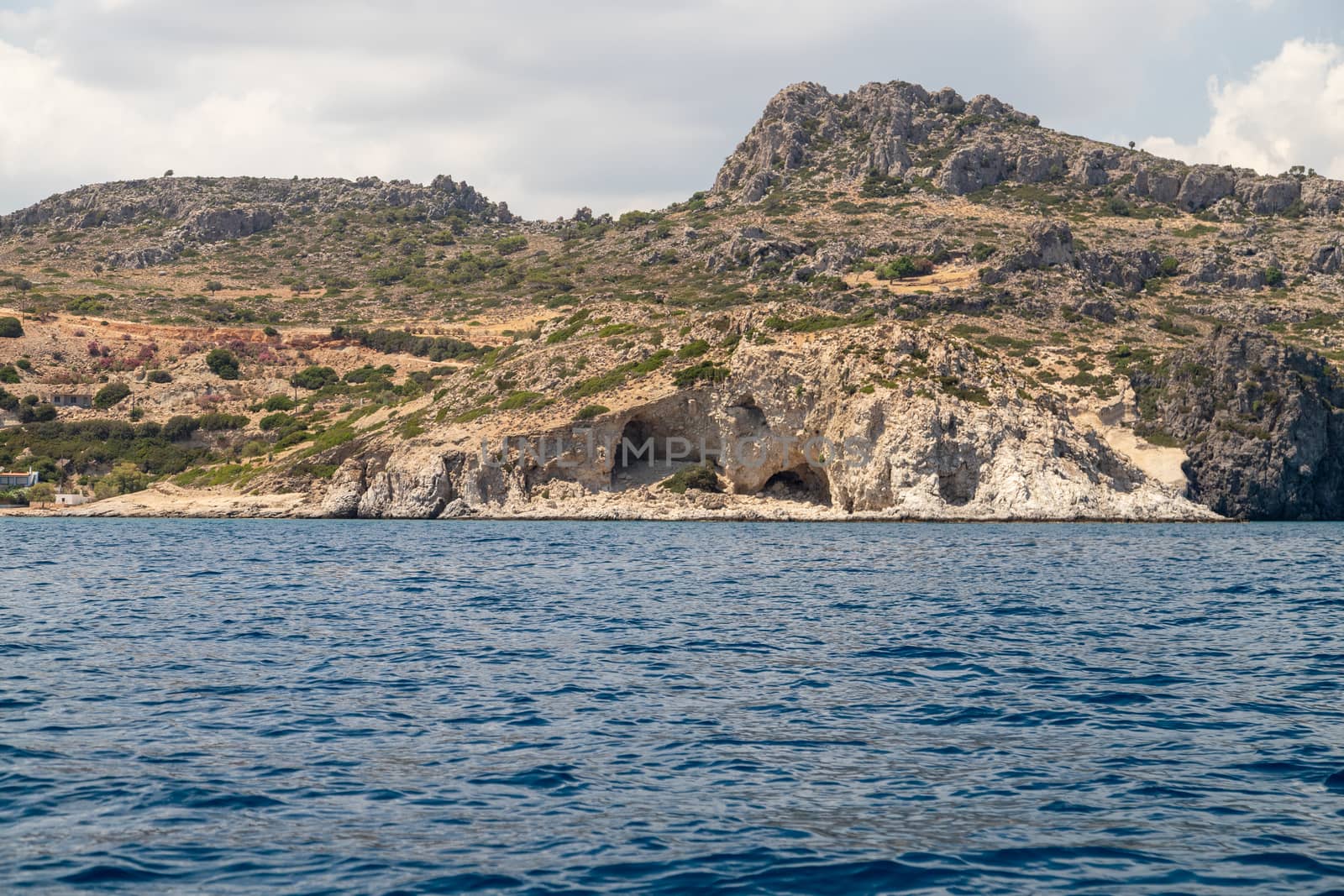 View from a motor boat on the mediterranean sea at the rocky coastline near Stegna on the eastside of Greek island Rhodes on a sunny day in spring