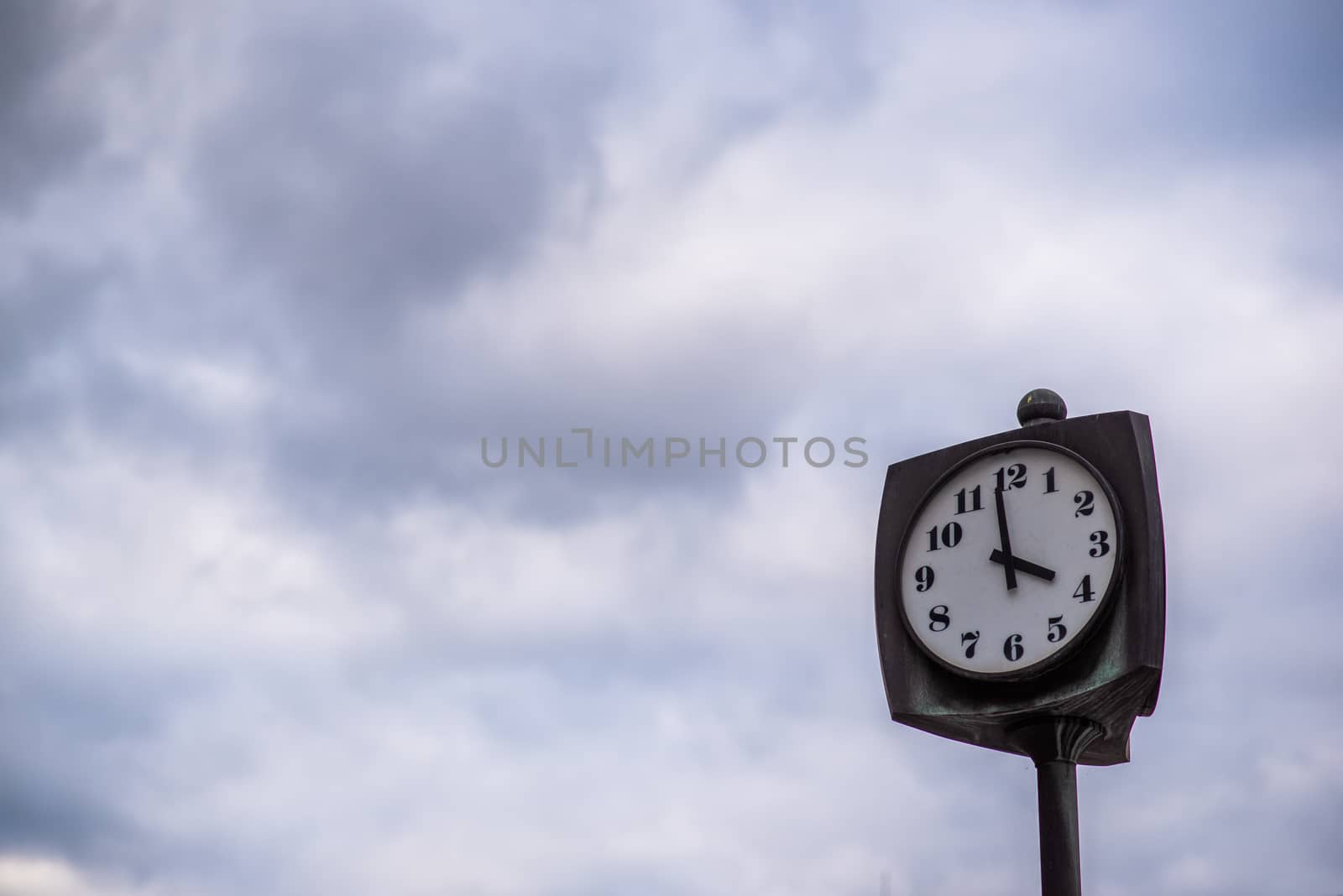 A clock outdoor in the city on a grey day