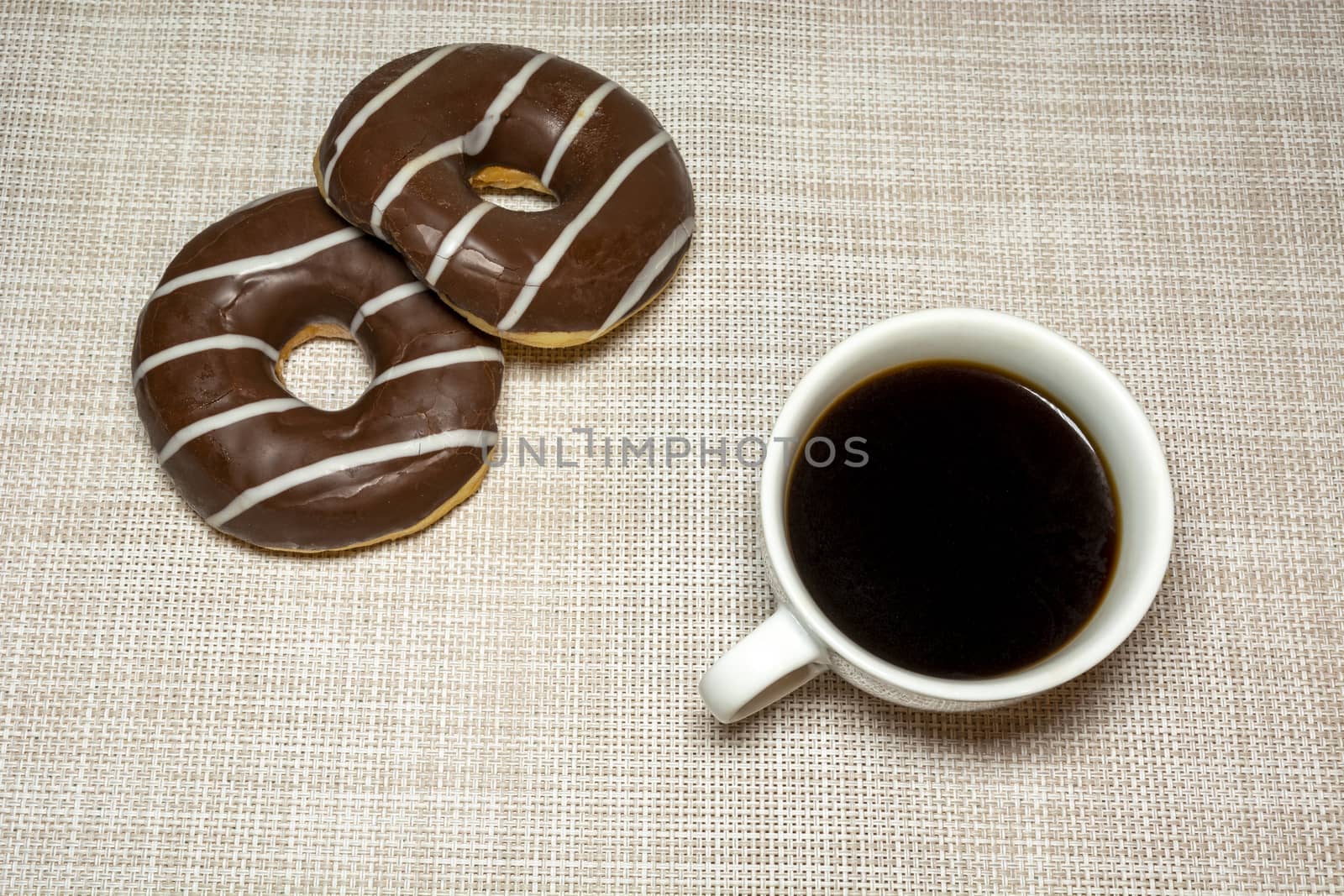 Coffee in a cup and two chocolate donuts, top view