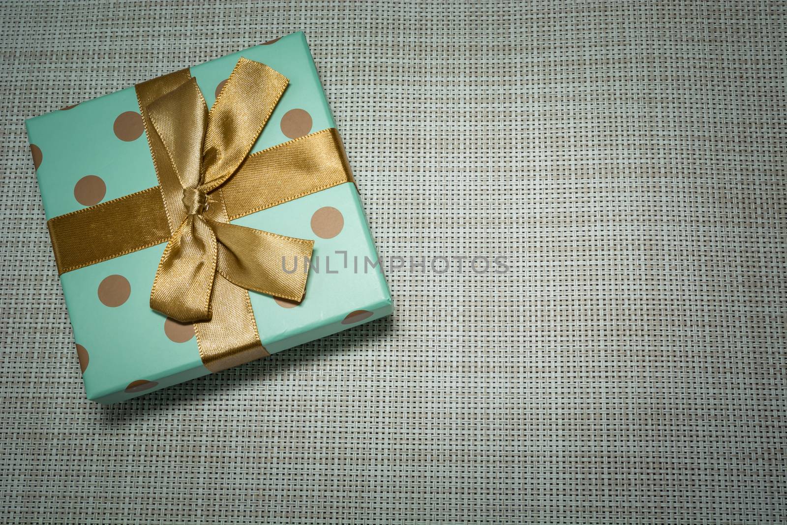 Gift wrapped in celadon paper and gold ribbon, top view