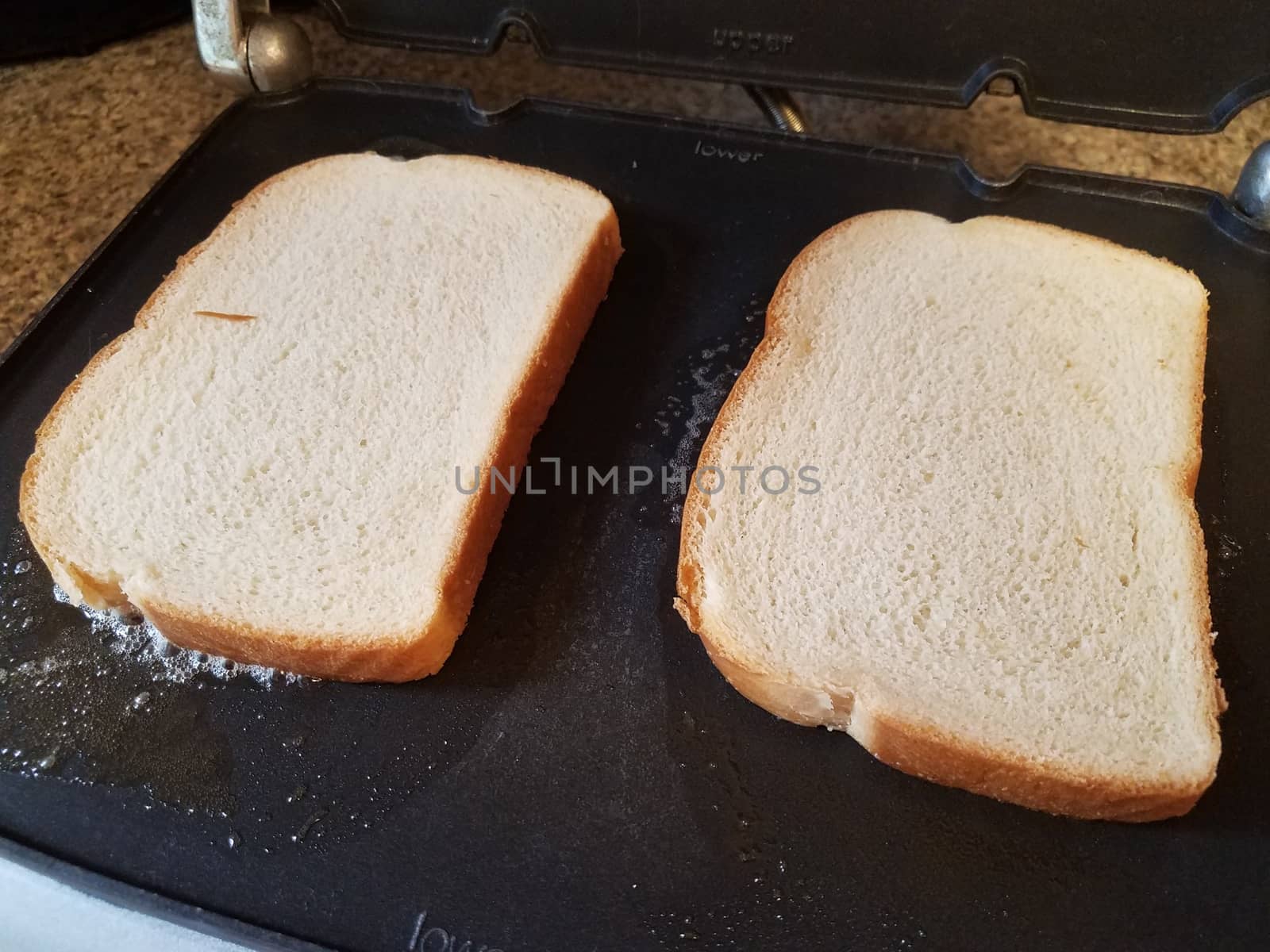 slices of white bread and butter cooking on grill