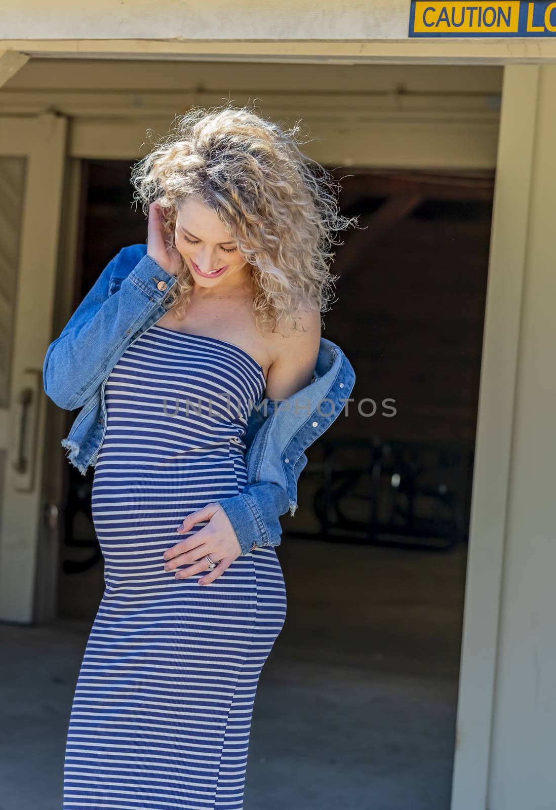 A pregnant blonde model poses for images in an outdoor environment