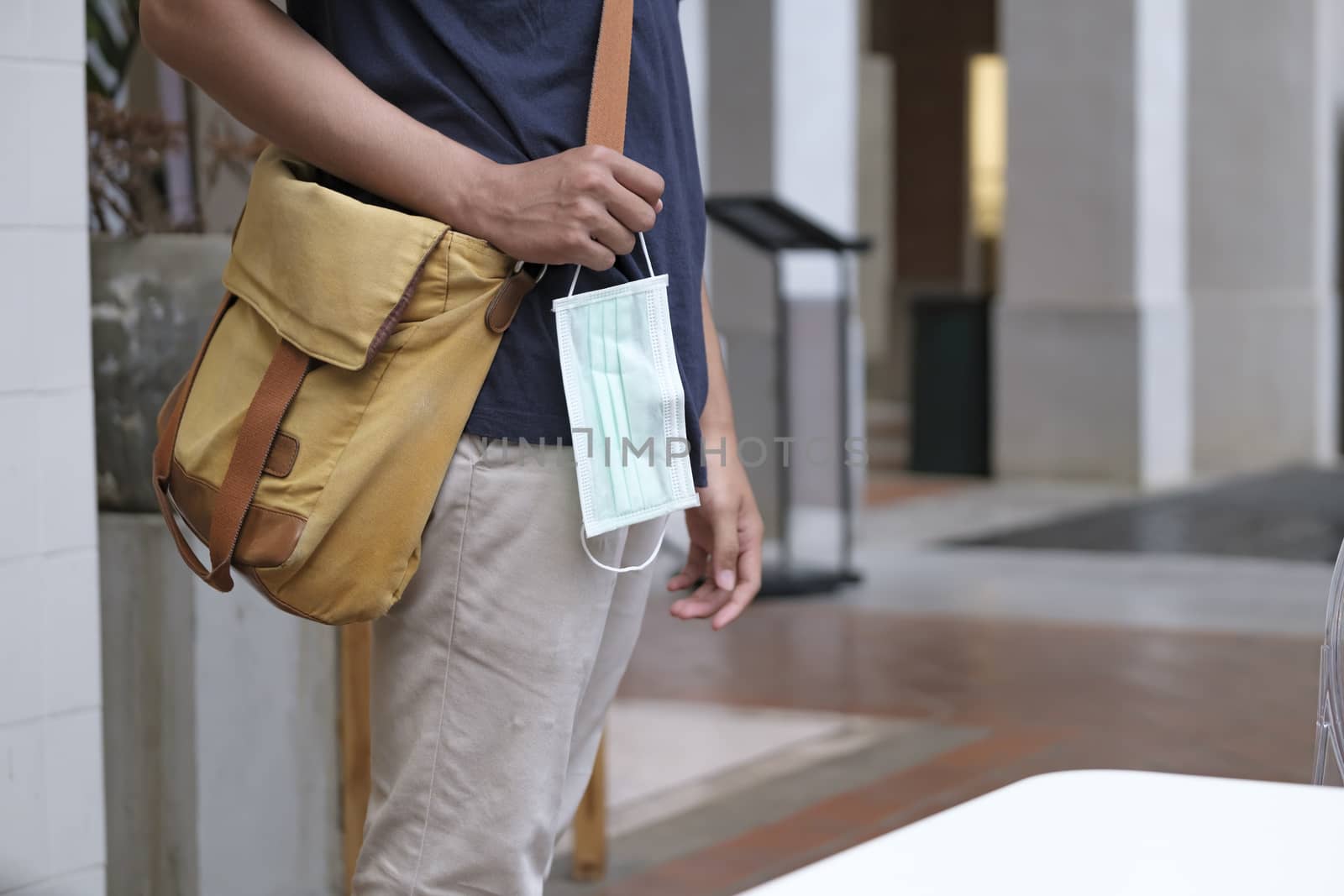 Closeup of a young man in an city street holding a surgical mask in his hand