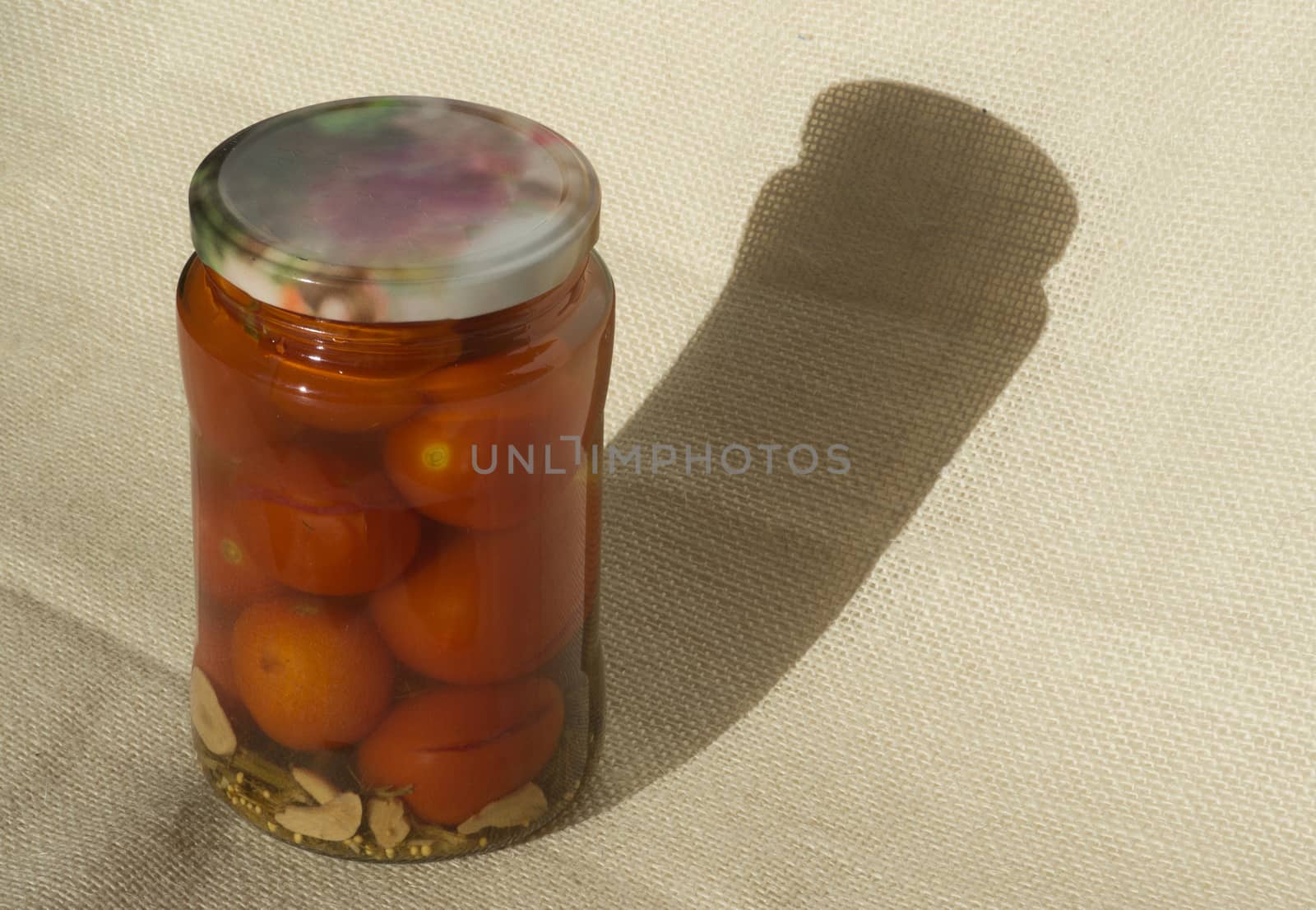 A jar of pickled tomatoes on a background of flax