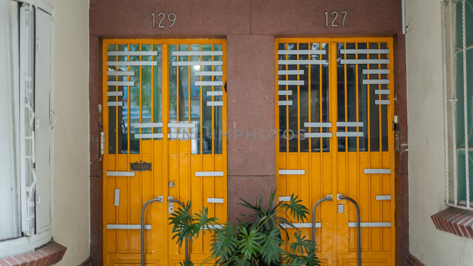 Picture of two orange doors from an apartment building with the numbers 129 and 127 over them