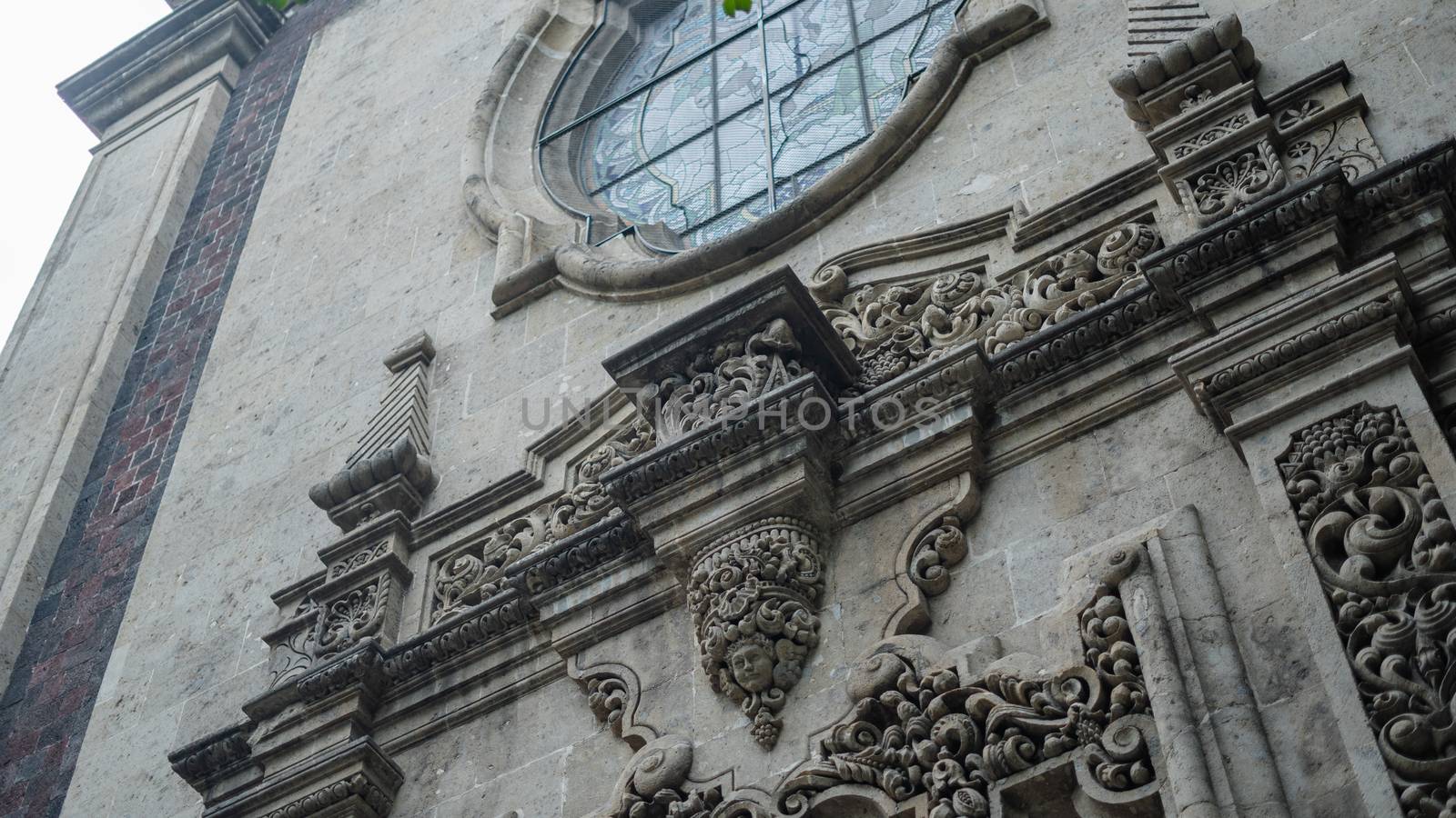 Low angle picture of a sculpted arch under a window from a building with byzantine architecture