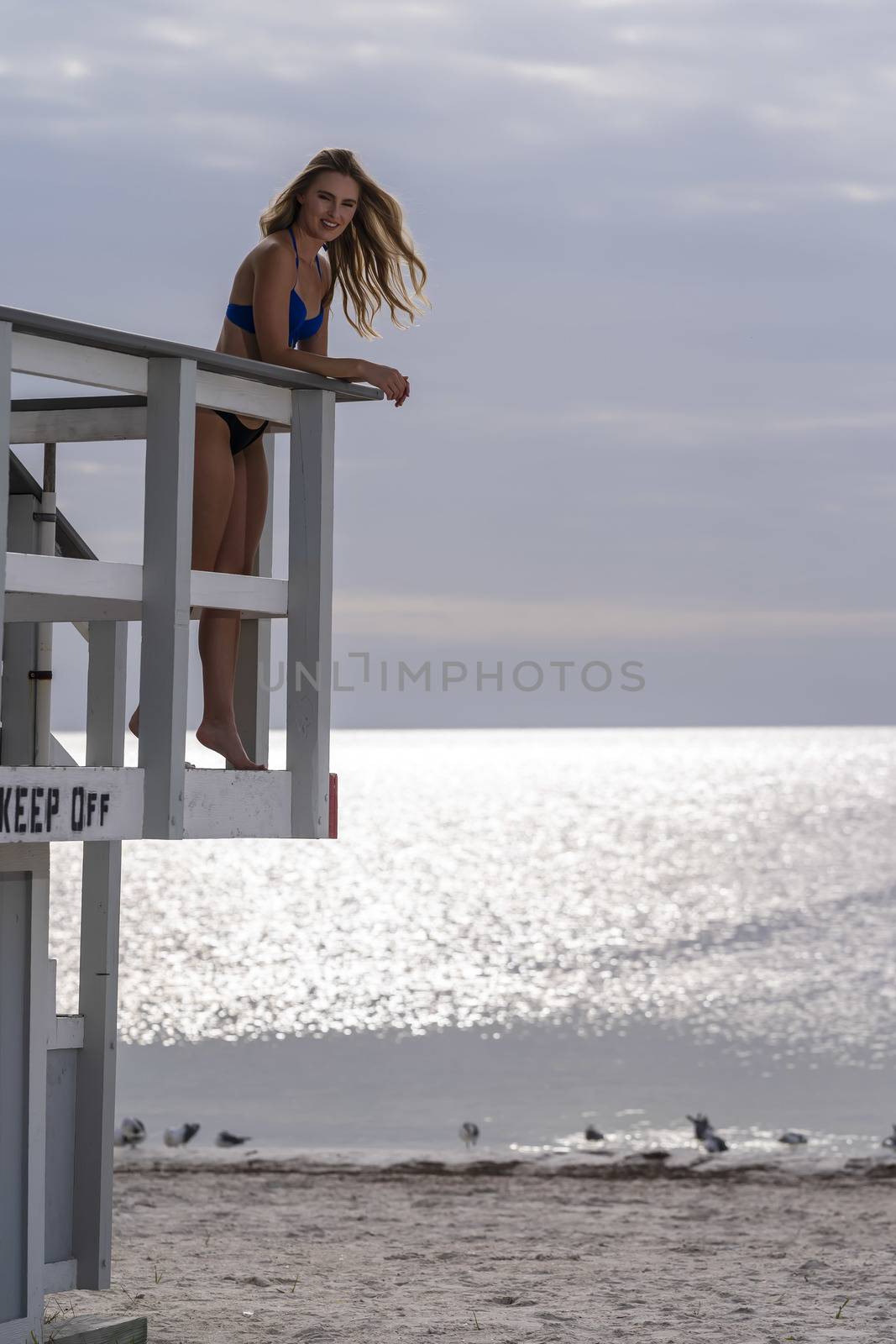 Lovely Blonde Bikini Model Posing Outdoors On A Caribbean Beach Near A Lifeguard Station by actionsports