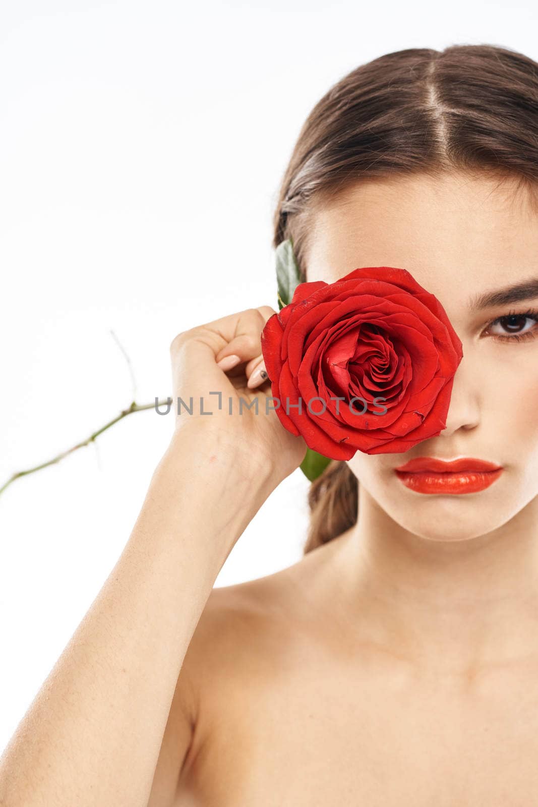 charming brunette girl with makeup on her face and a red rose in her hand. High quality photo