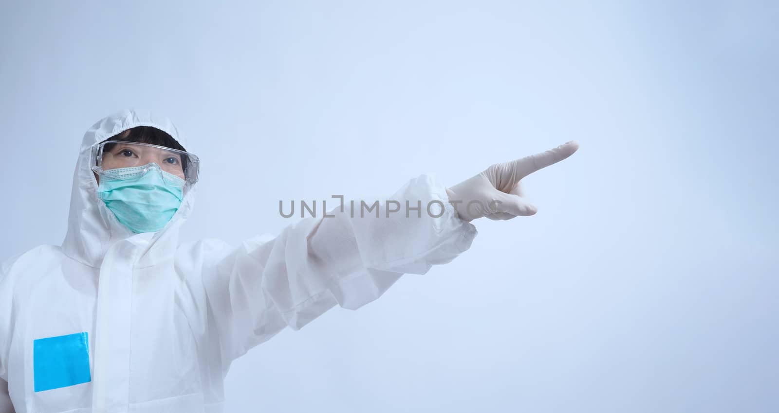 Asia woman doctor in PPE suit or Personal Protective Equipment uniform and wearing medical face mask, rubber gloves and goggles for protect coronavirus pandemic. Studio shot with copy space.