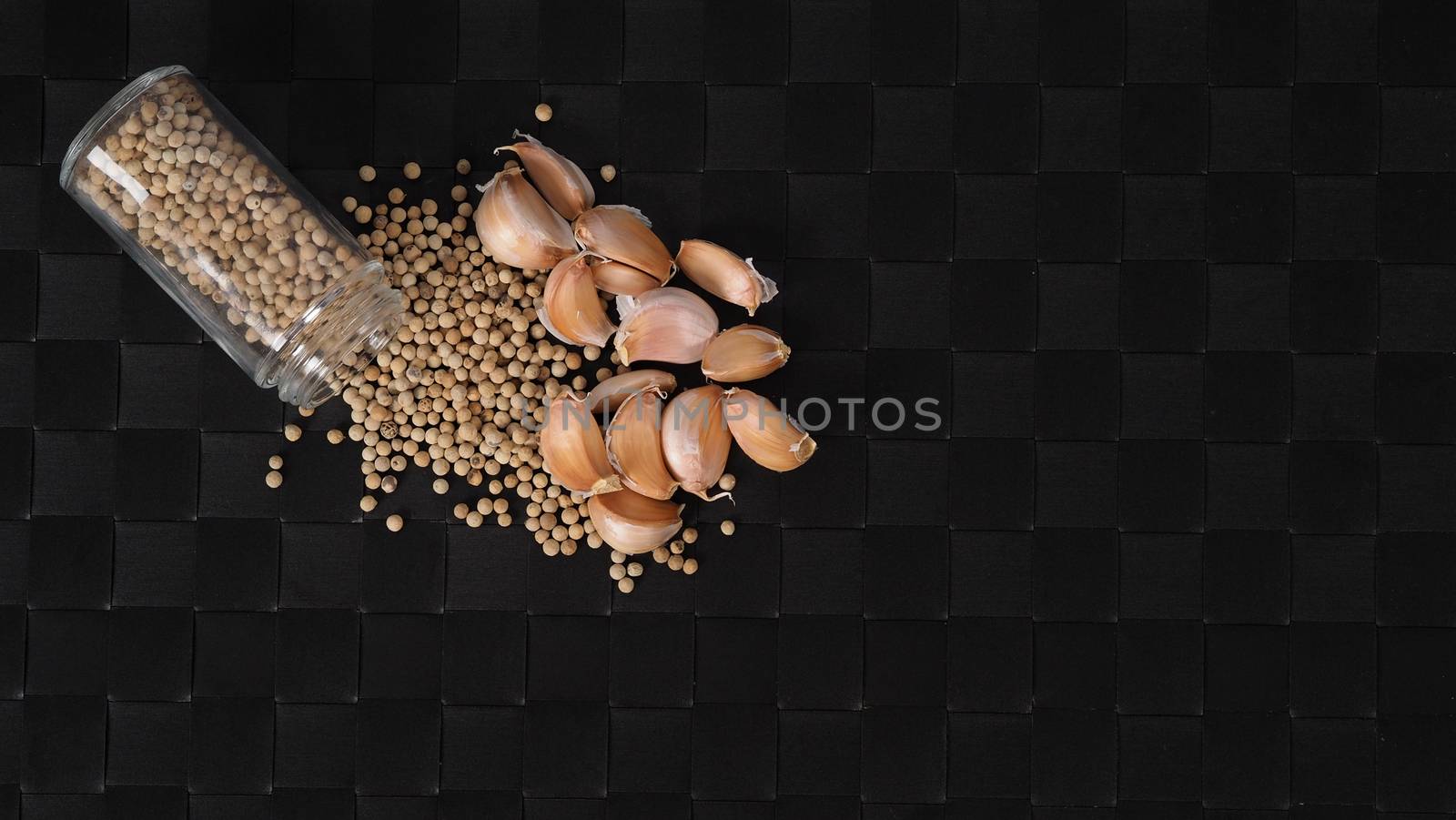 Natural Garlic and white peppercorn in glass bottle on plate mat by gnepphoto