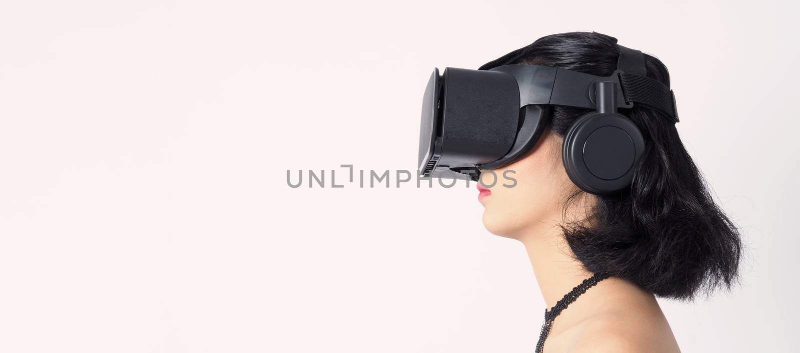 Asian teen woman wearing VR or Virtual Reality head set for enter to the digital simulation world for learning and traveling or gaming  and more. Studio shot white background