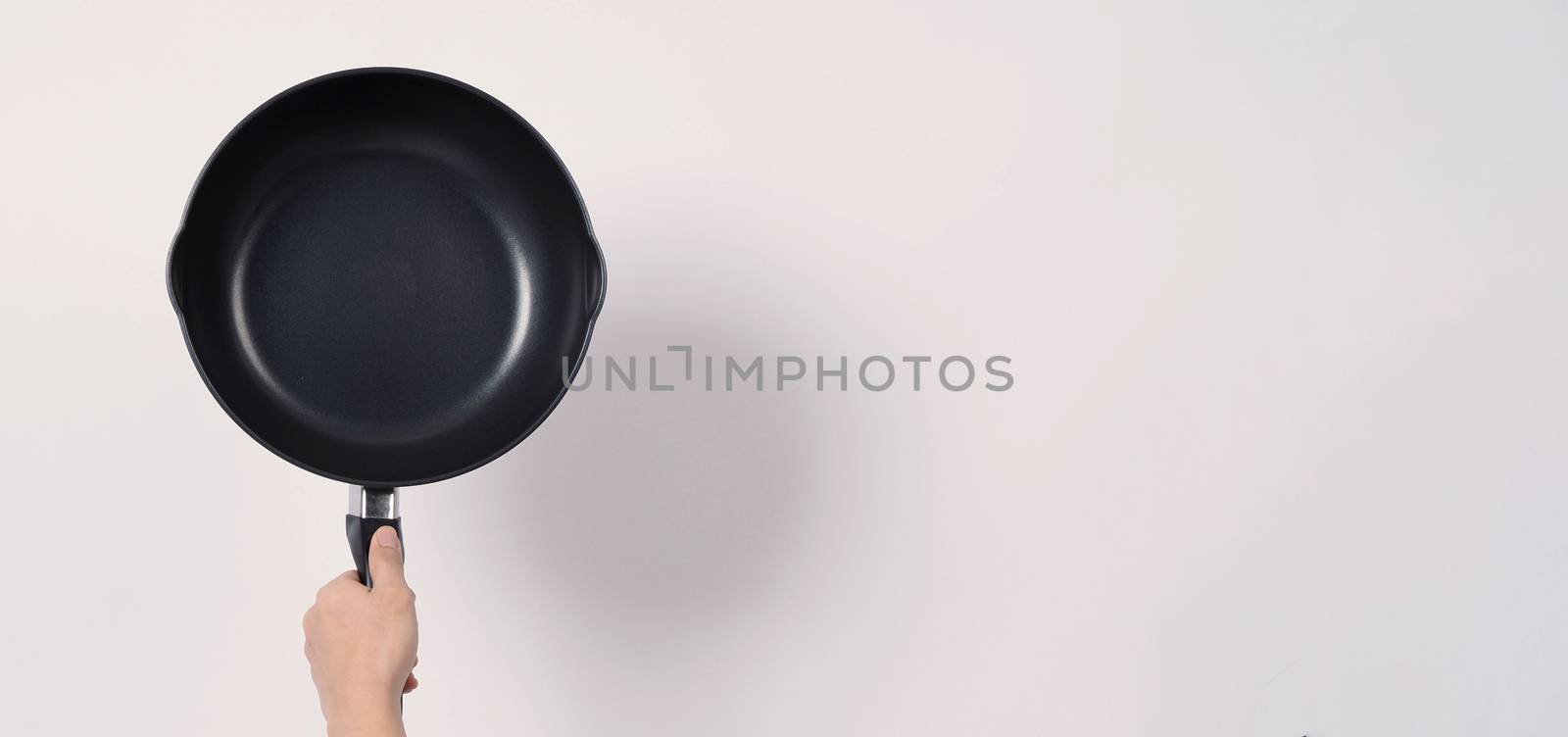 Asian man in grey color T shirt cleaning the non stick pan with handy dishwashing sponge which yellow color on the soft side and green on hard side for hygiene after cook and white background studio shot