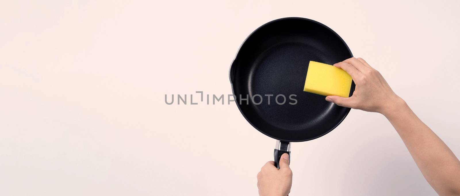 Asian man in grey color T shirt cleaning the non stick pan with handy dishwashing sponge which yellow color on the soft side and green on hard side for hygiene after cook and white background studio shot