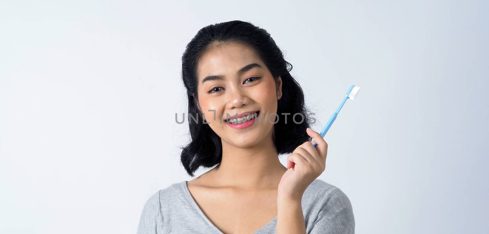 Asian teen facial with braces and smiling to camera to show dental orthodonic teeth which include professional metal wire material from orthodontist. studio shot white background.