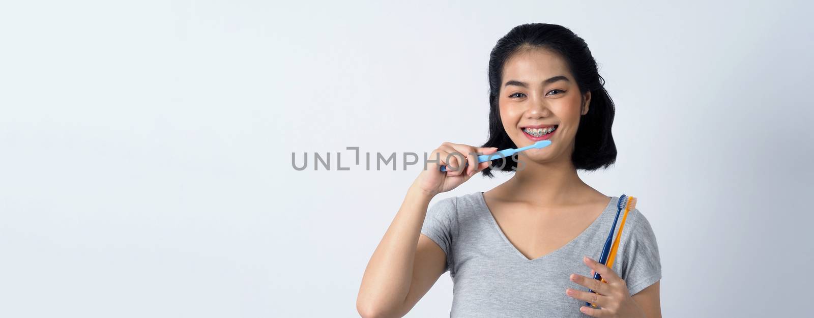 Asian teen facial with braces and smiling to camera to show dental orthodonic teeth which include professional metal wire material from orthodontist. studio shot white background.