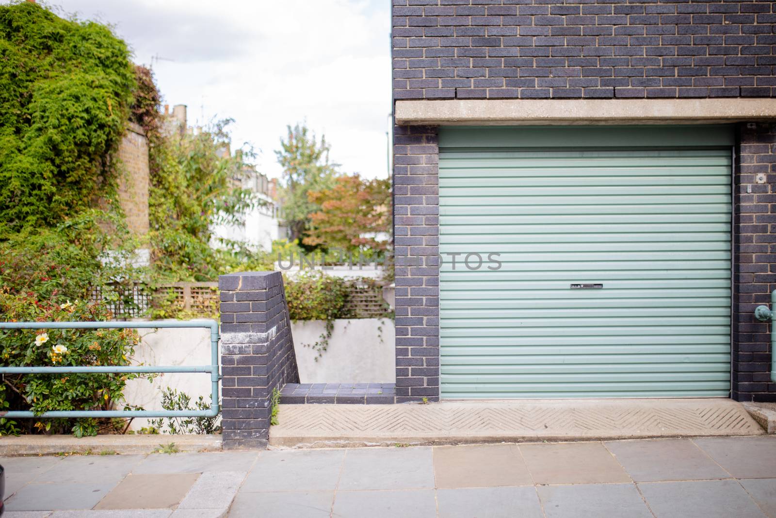 Landscape View of the Garage Door of a Dark Colour Brick Building with trees in the background and from London, UK