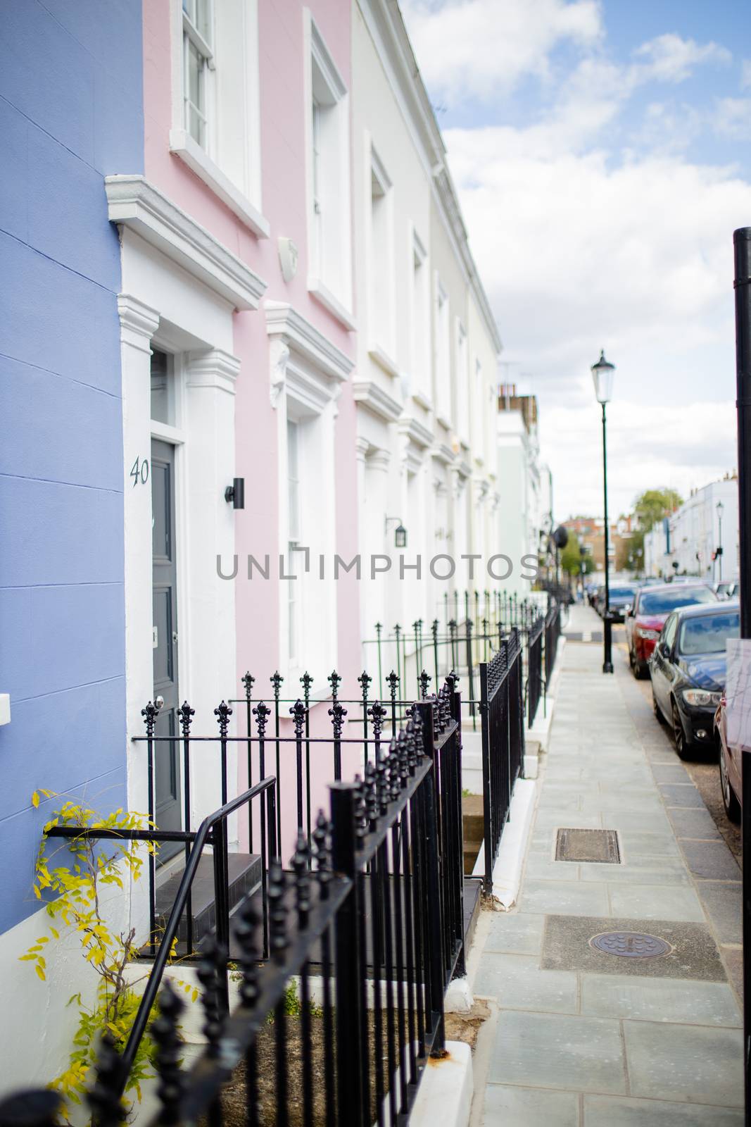 Portrait style picture of a neighbourhood from London with colorful houses and cars parked outside