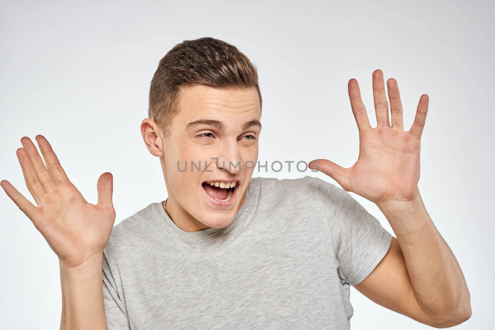 Cheerful emotional man gray t-shirt gesturing with hands studio lifestyle by SHOTPRIME