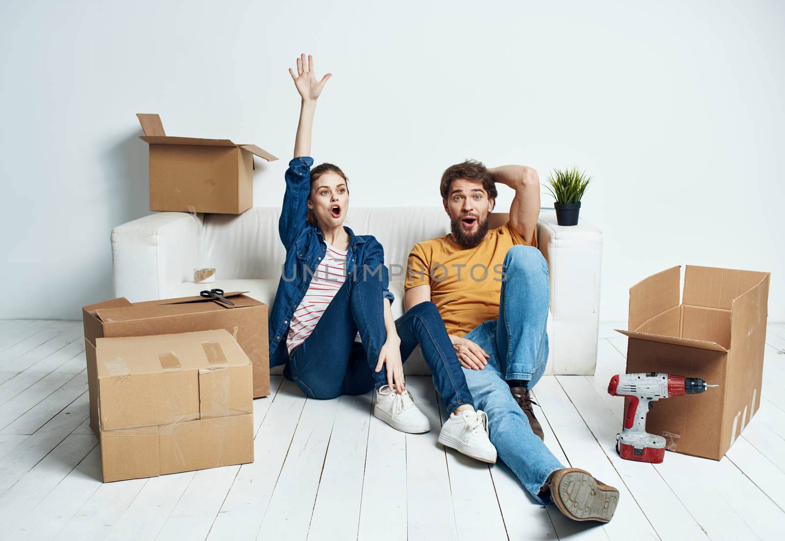 A man and a woman are sitting on the floor with open boxes and tools for repair. High quality photo