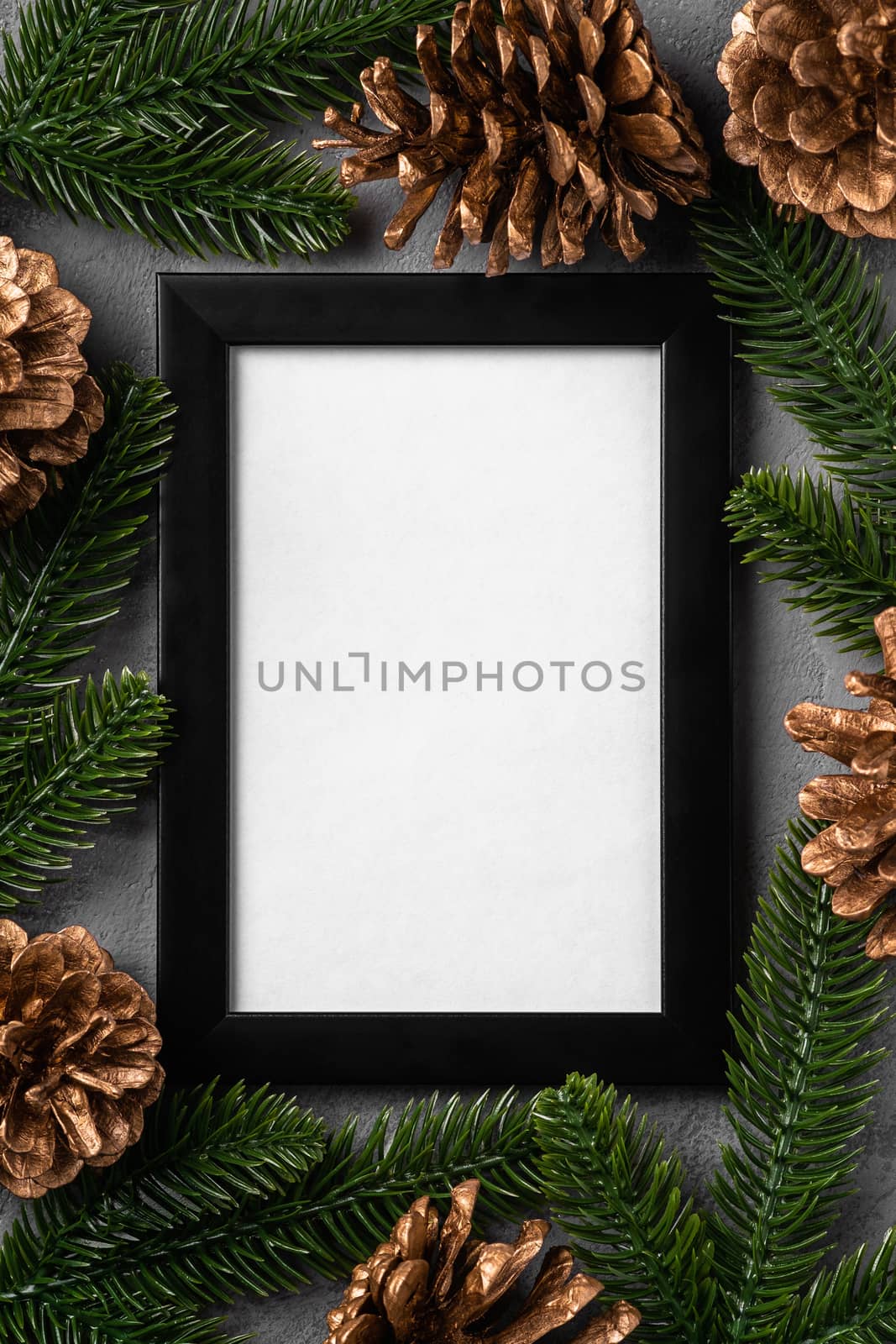 Christmas composition with empty picture frame. Golden ornament, pine cones and fir needles decorations. Mock up greetings card template