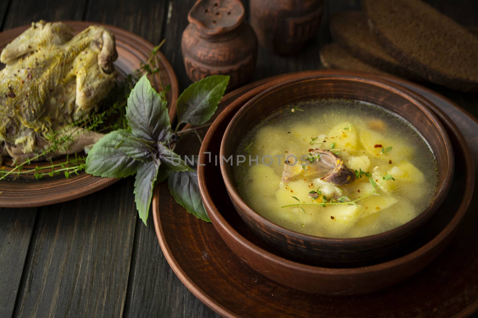 Partridge soup with basil in a rustic bowl on dark wooden table