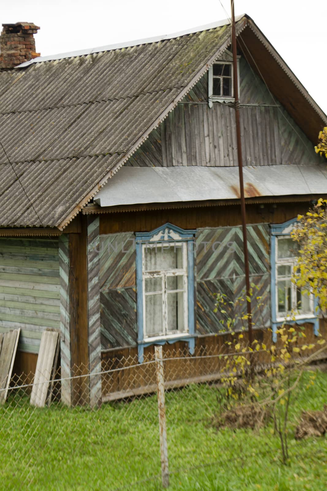 Old traditional wooden house with slate roof in village, Belarus. Vertical image