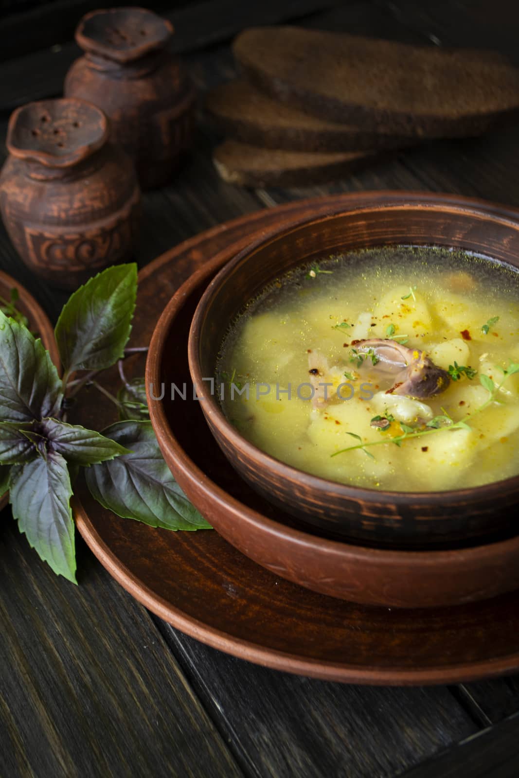 Wild partridge soup in a pot with vegetables on old wooden background