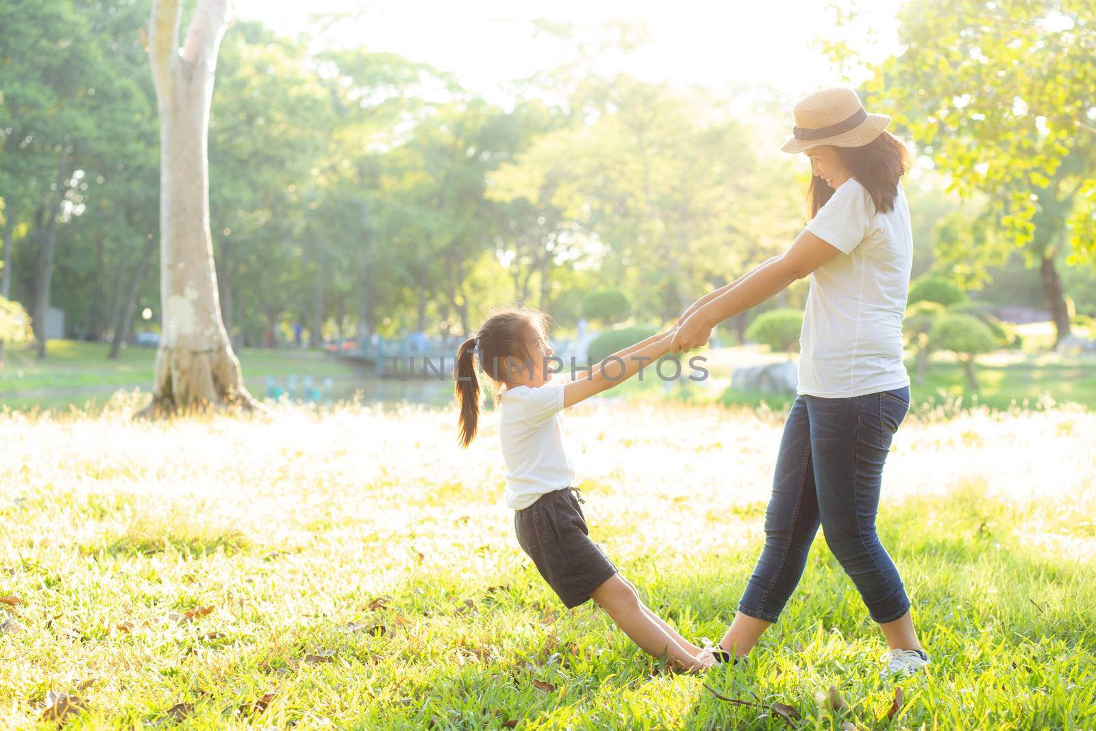 Young asian mother and little daughter playing the park with fun and happiness, family enjoy and relax and leisure together, mom and children smiling laughing in summer day.