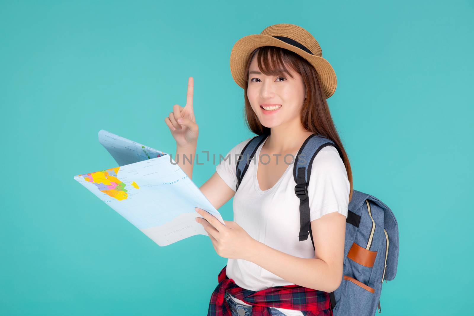 Beautiful happy young asian woman travel holding and looking a paper map isolated on blue background, asia girl pointing and search journey with direction in vacation trip with cheerful for leisure.