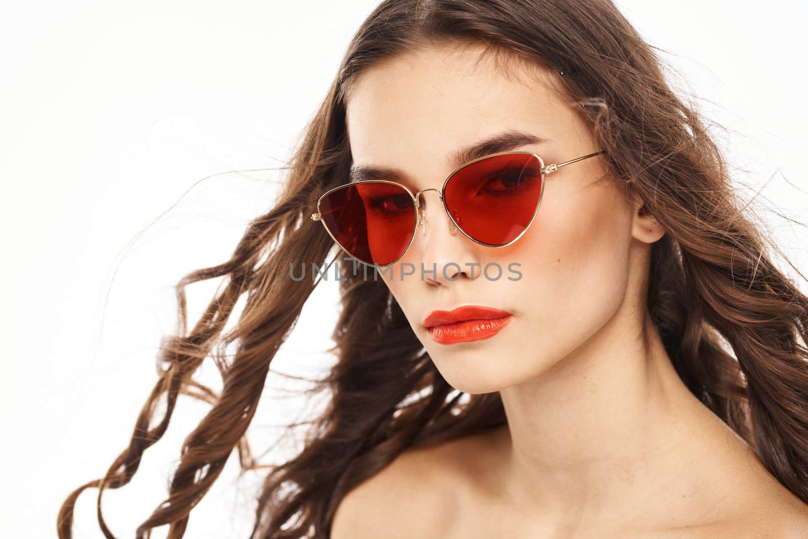 Portrait of brunette woman in sunglasses naked shoulders light background. High quality photo