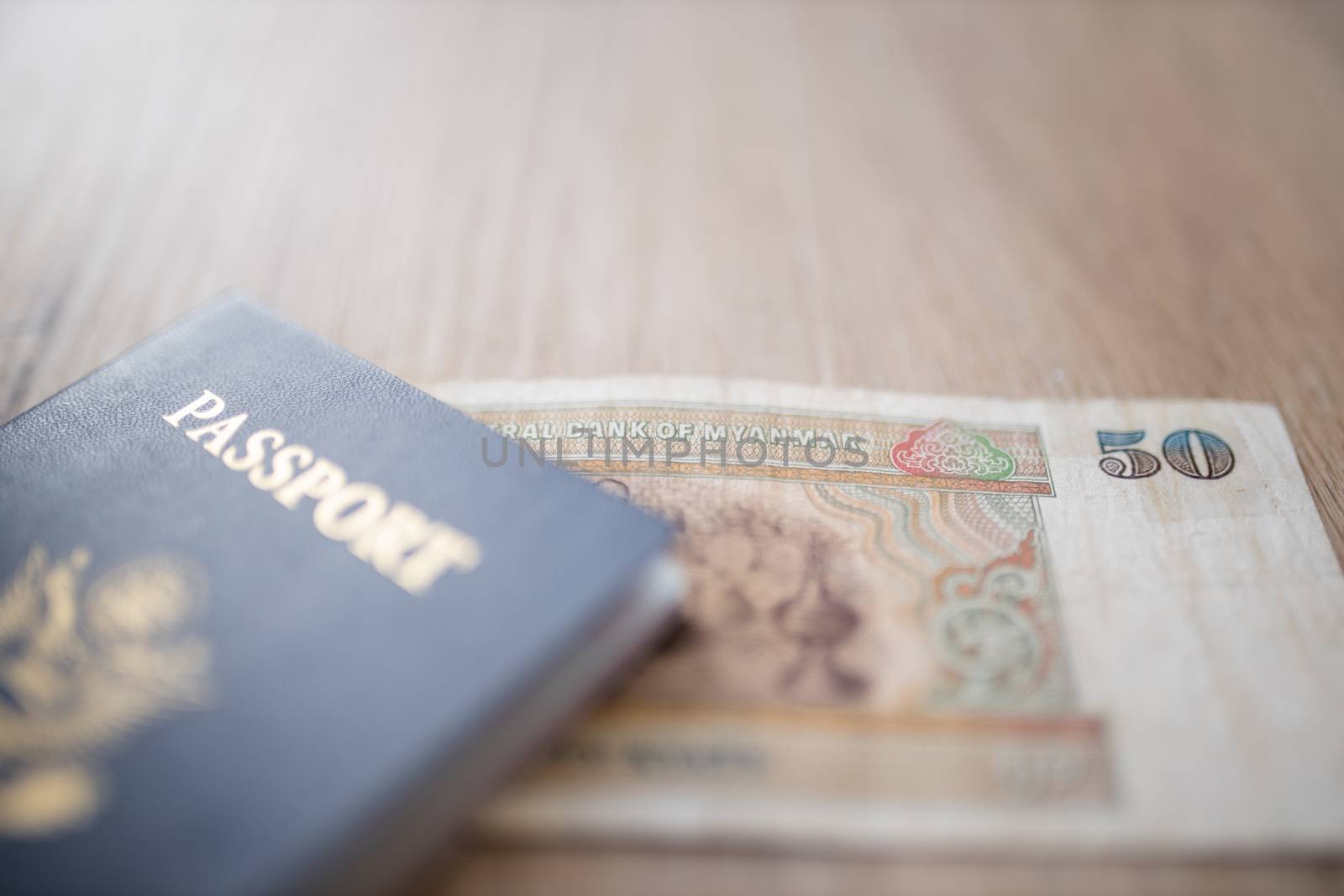 Picture of a blurry United States of America Passport partially on top of a Fifty Burmese Kyats Bill