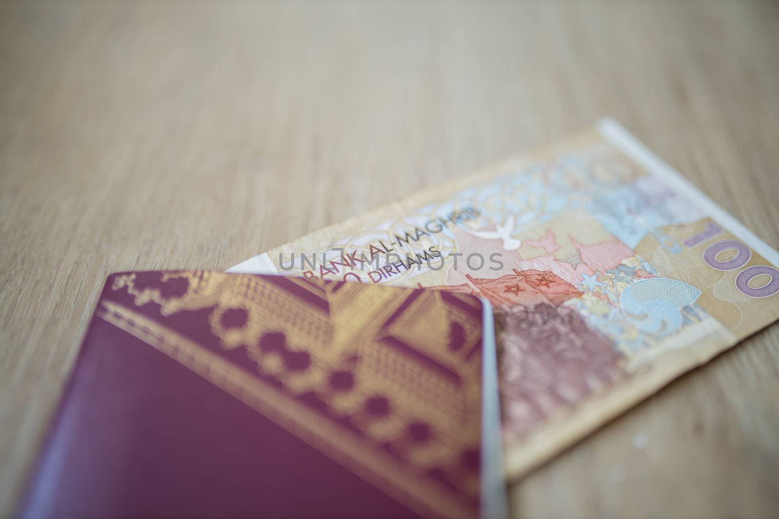 Picture of a 100 Moroccan Dirhams Bill Partially Inside a blurry Sweden Passport