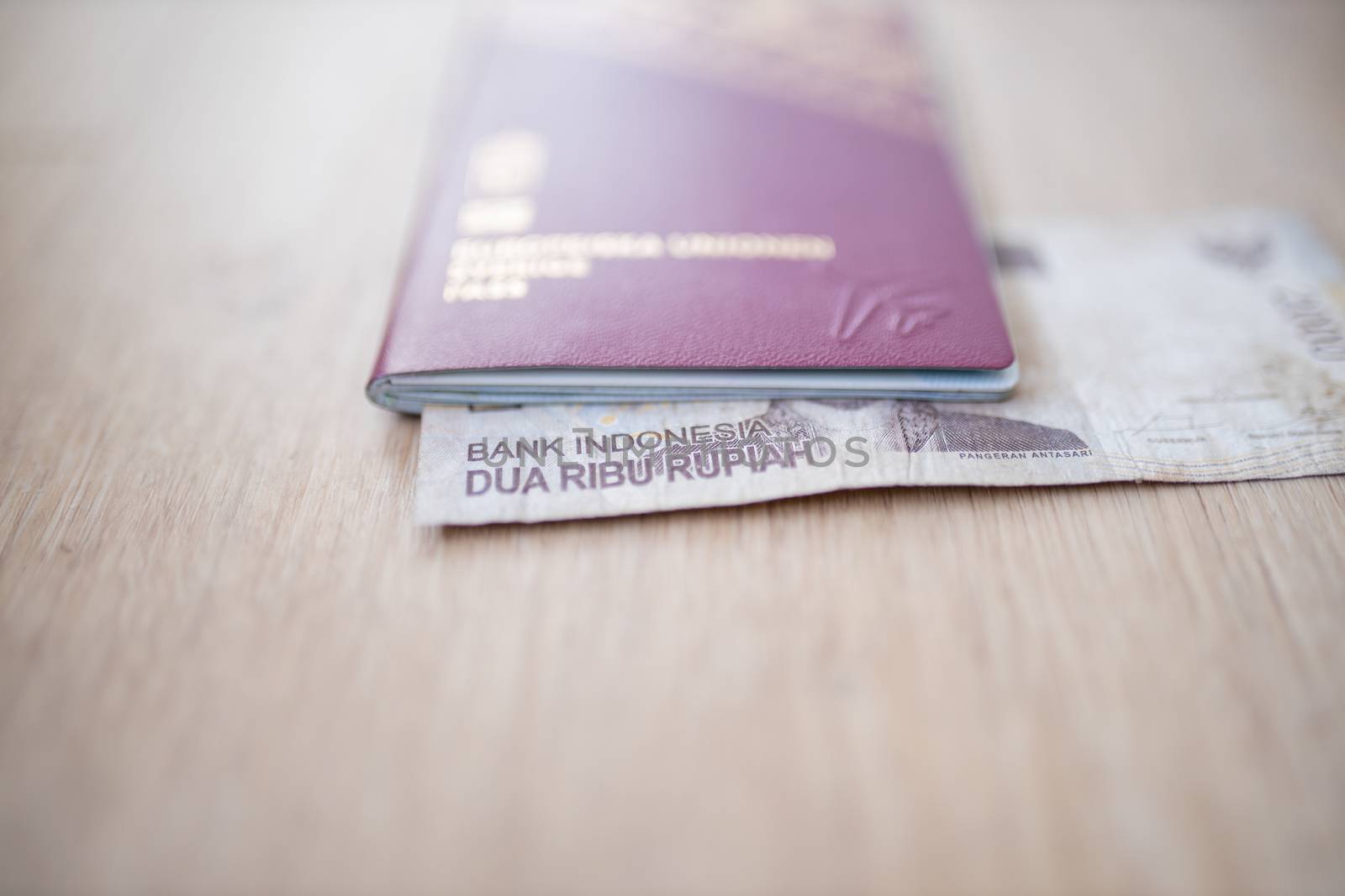 Picture of a 2000 Indonesian Rupees Bill -with the words Indonesia Bank and Two Thousand Rupees in Indonesian- Inside a blurry Sweden Passport
